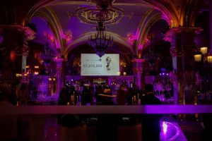 La salle plongée dans l'obscurité avec des lumières violettes et l'écran montrant le montant récolté durant la soirée.