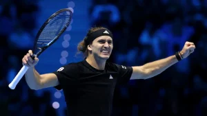Un joueur de tennis lève les bras et grimace après sa victoire.