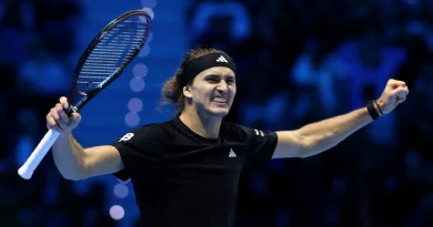 Un joueur de tennis lève les bras et grimace après sa victoire.