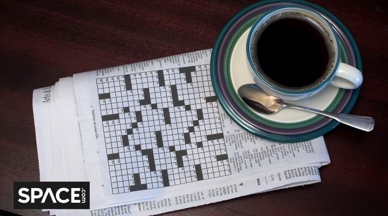 A black and white crossword puzzle sits underneath a blue and white coffee cup with the Space.com black and white logo in the bottom left corner.