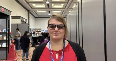 Une femme portant des lunettes regarde la caméra en souriant