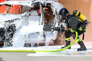 Extinction d'un incendie de véhicule par un pompier.
