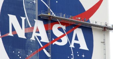 workers on scaffolding paint a nasa logo on a massive white building