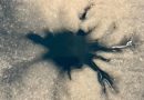 A dendritic shaped dark spot is seen against an icy surface