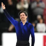 Un patineur salue la foule de sa main droite à la fin de son programme.
