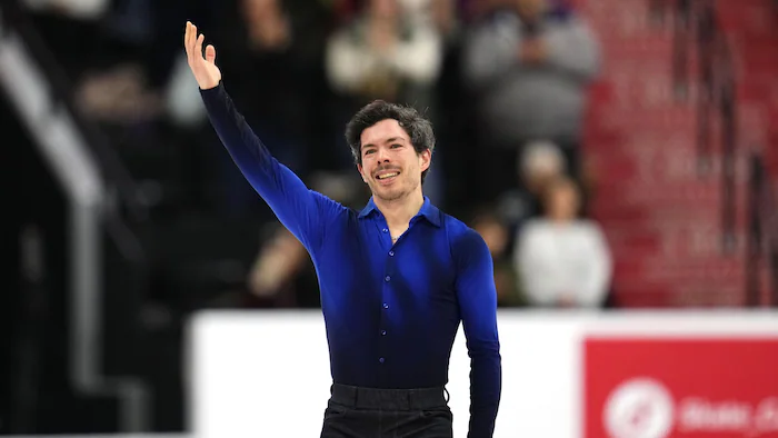 Un patineur salue la foule de sa main droite à la fin de son programme.