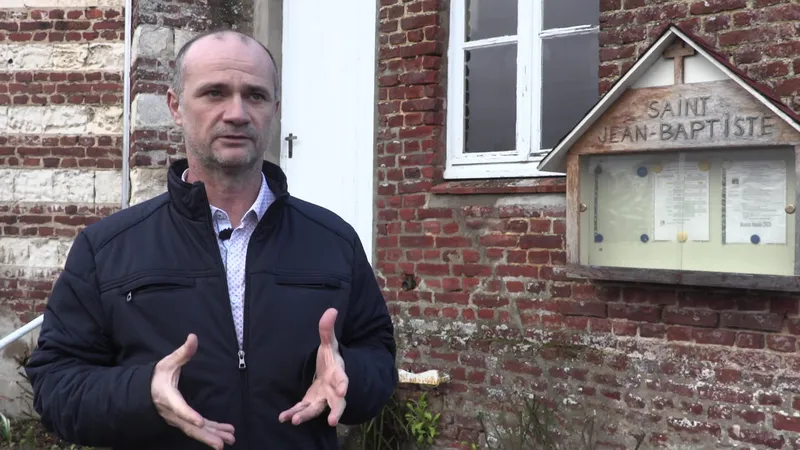 Allan Turpin, maire (SE) d'Andres, devant l'église Saint Jean-Baptiste. L'édifice a désormais une bière à son nom.