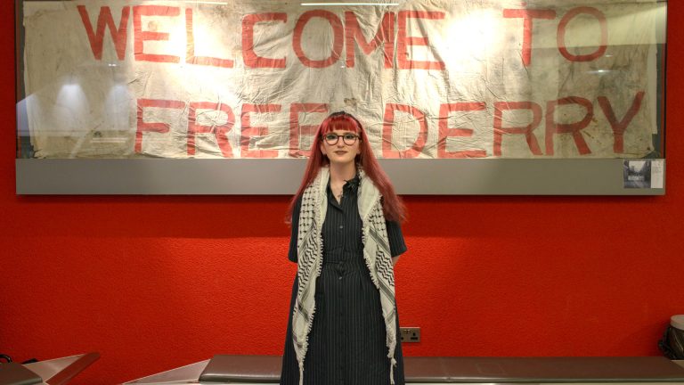 Caitlin Askin, du musée "Free Derry", pose devant une banderole exposée au musée. Derry, 30 janvier 2026.