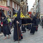 Des pénitents de la procession de la Sanch défilent dans les rues de Perpignan lors du Vendredi saint, portant une statue du Christ au cœur du centre historique.