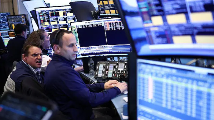 Des opérateurs de Wall Street dans le feu de l'action devant une foule d'écrans.