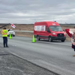 Des manifestants sur la route agitent des drapeaux.