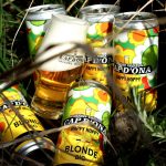 Des canettes de Happy Hoppy® Blonde Bio de Cap d’Ona entourent un verre de bière, image du nouveau format lancé par la brasserie de Céret.