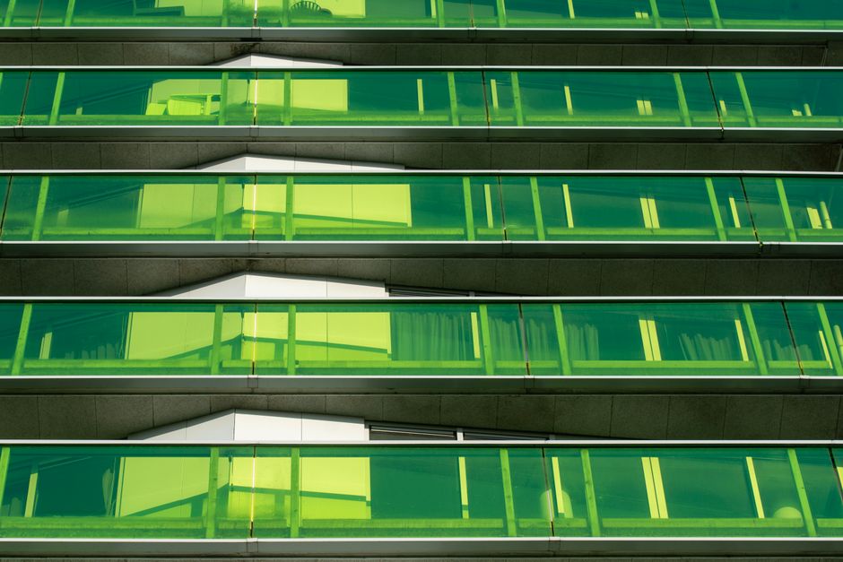 Graphic abstract view of a modern building with green glass facades and balconies.