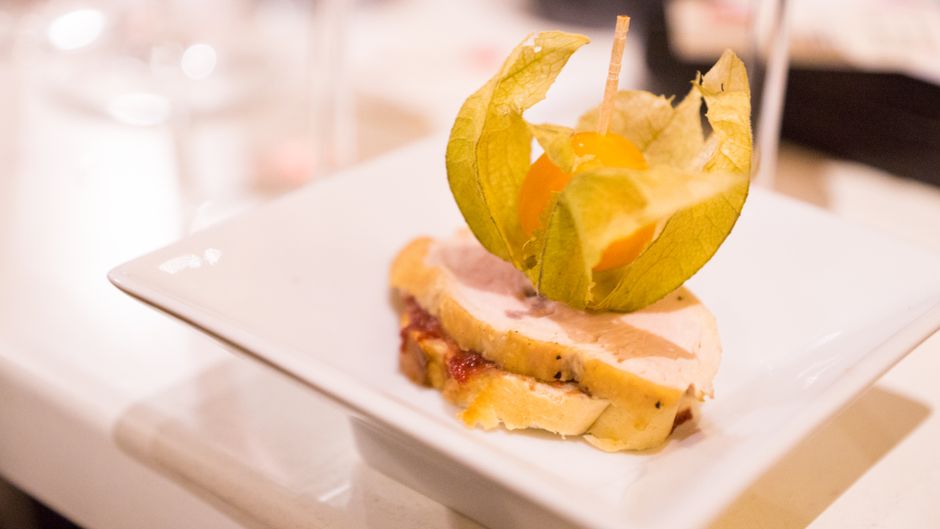 Gourmet turkey slice topped with a physalis garnish on a white plate, served indoors.
