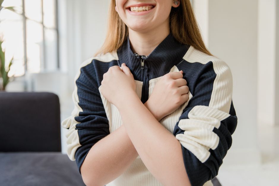 Cheerful woman posing with crossed arms, expressing happiness indoors.