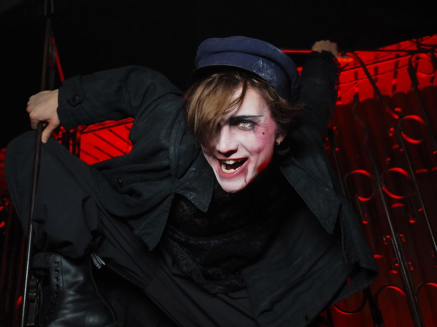 A performer in a spooky Halloween costume with dramatic makeup and expression.