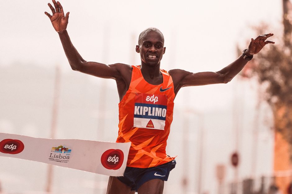 Runner crossing the finish line at a marathon in Lisbon, showcasing victory and achievement.