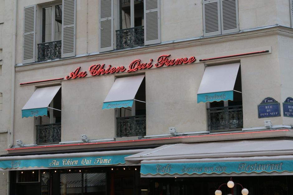 Elegant facade of a Parisian café, Au Chien Qui Fume, with vintage signage and awnings.