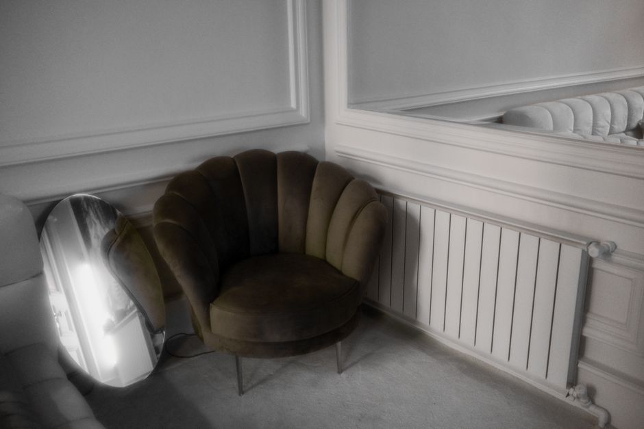 A stylish room featuring a modern armchair and decorative mirror reflecting its sophisticated decor.