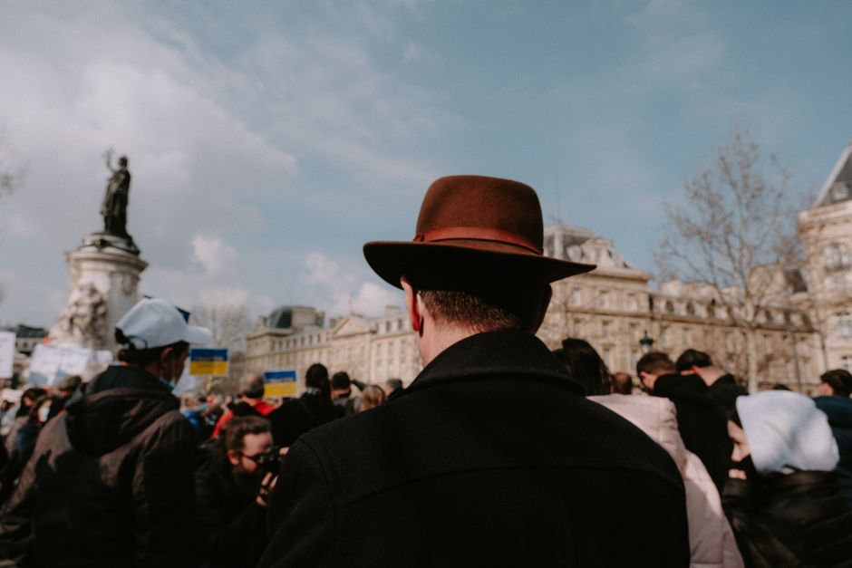 A diverse group gathers at Place de la République under a clear sky.