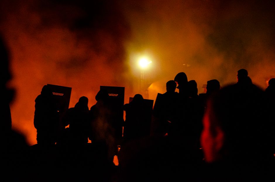 Dramatic scene of silhouetted police with shields against a smoky night backdrop in Lviv.