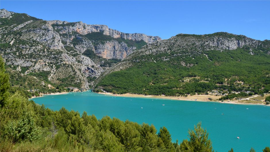 Aerial view of turquoise lake surrounded by lush mountains in Aiguines, France.