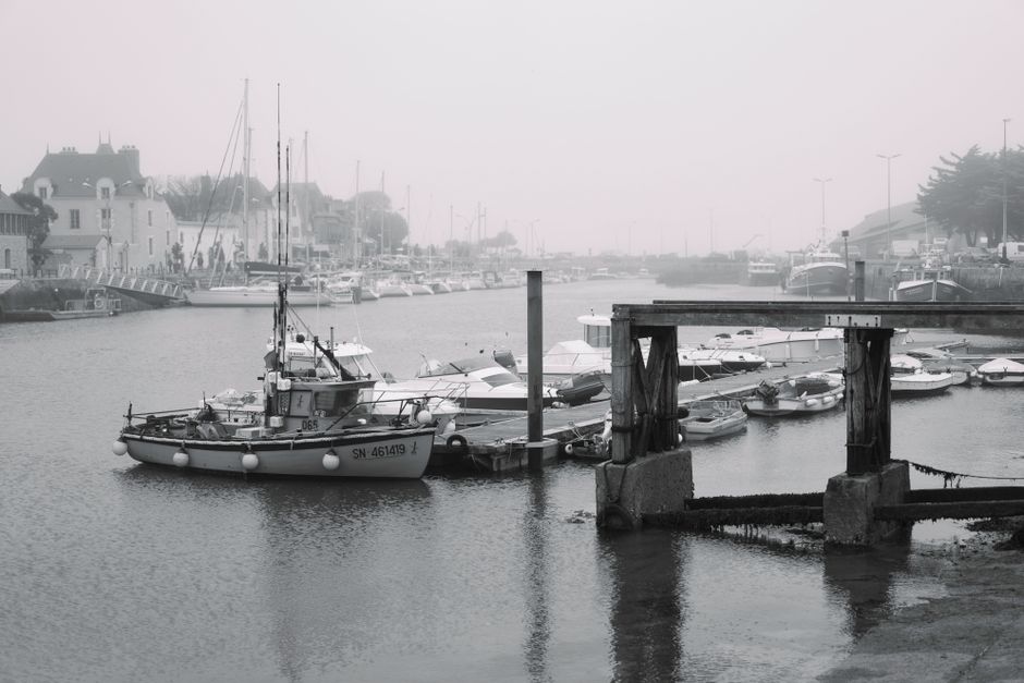 A captivating black and white photo of a serene harbor with boats docked in Le Croisic, France.