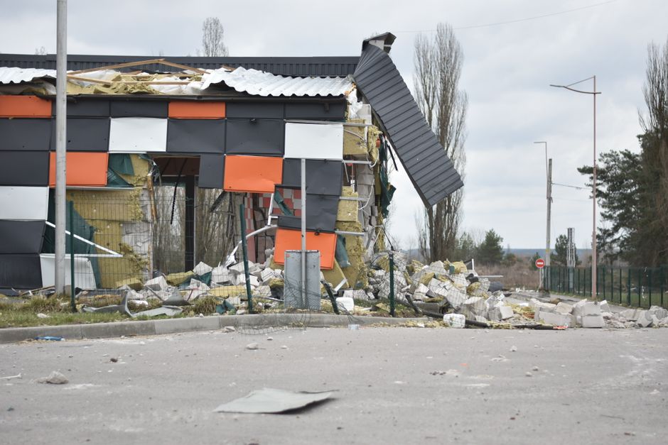 Urban scene of a partially destroyed building with debris and broken materials on the street.