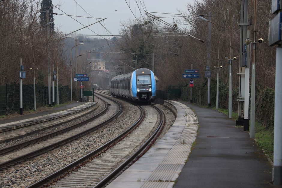 A passenger train approaches a railway station in Saint-Ouen-l'Aumône, France.