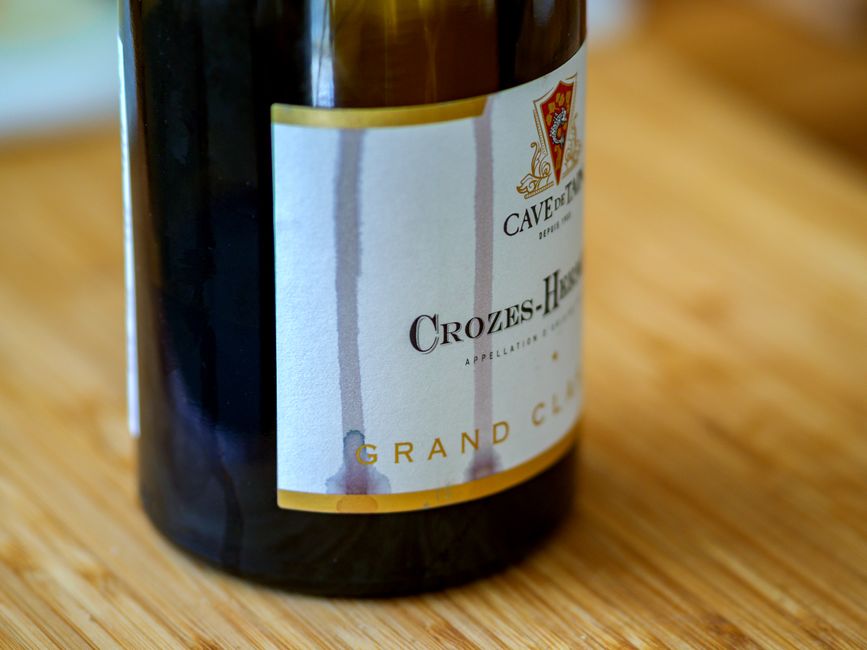 Detailed close-up view of a Crozes-Hermitage wine bottle on a wooden surface.