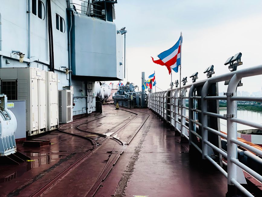 Explore the industrial ship deck adorned with international flags at Tianjin's harbor.