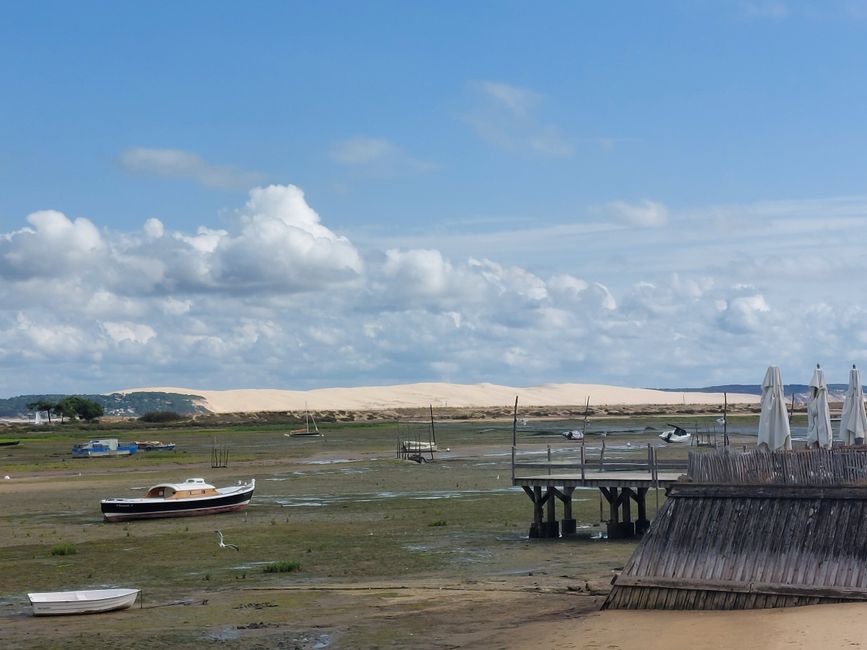 Explore the serene French coast with boats stranded on shore during low tide, under a bright blue sky.