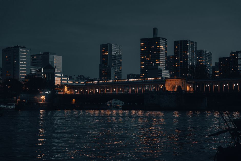 Nighttime view of Paris skyline with illuminated buildings reflected on the river.