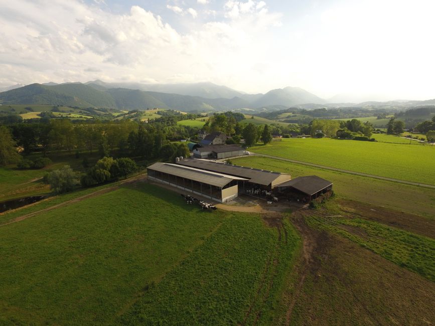 Aerial view of a scenic farm in Asson, Nouvelle-Aquitaine, France with beautiful mountain backdrop.
