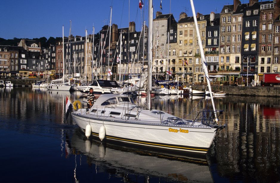 Scenic view of Honfleur harbor in Normandie with yachts and quaint architecture reflecting in the water.
