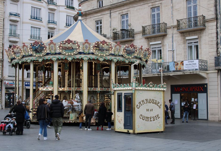 Vintage carousel in Lyon, France with lively street scene and historic buildings.