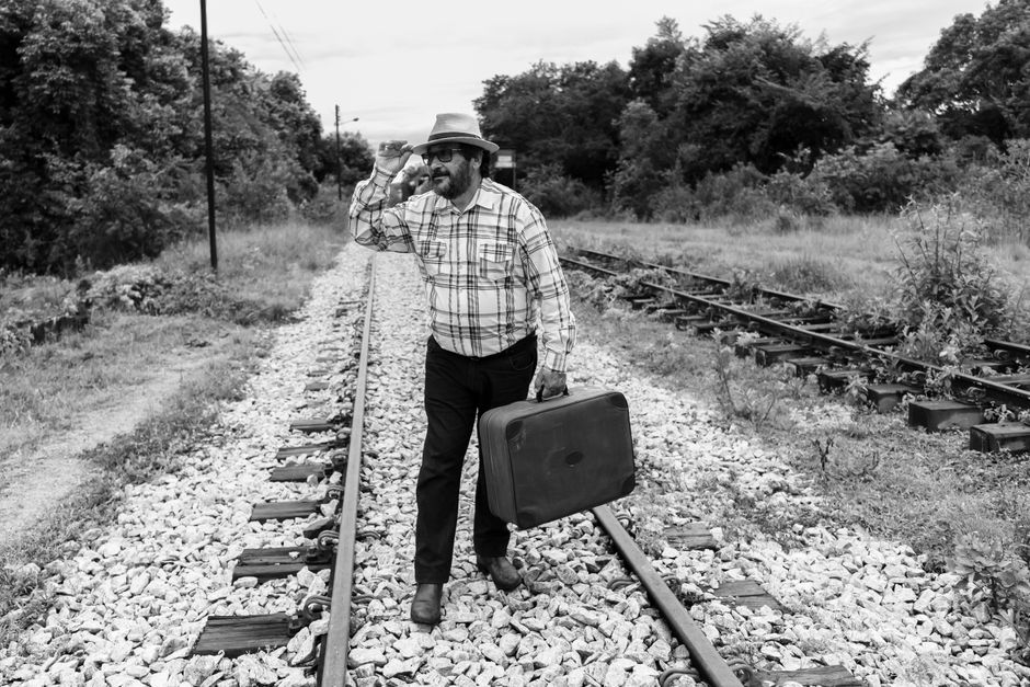 Man with suitcase walking on railway tracks in Itapecerica, Brazil.