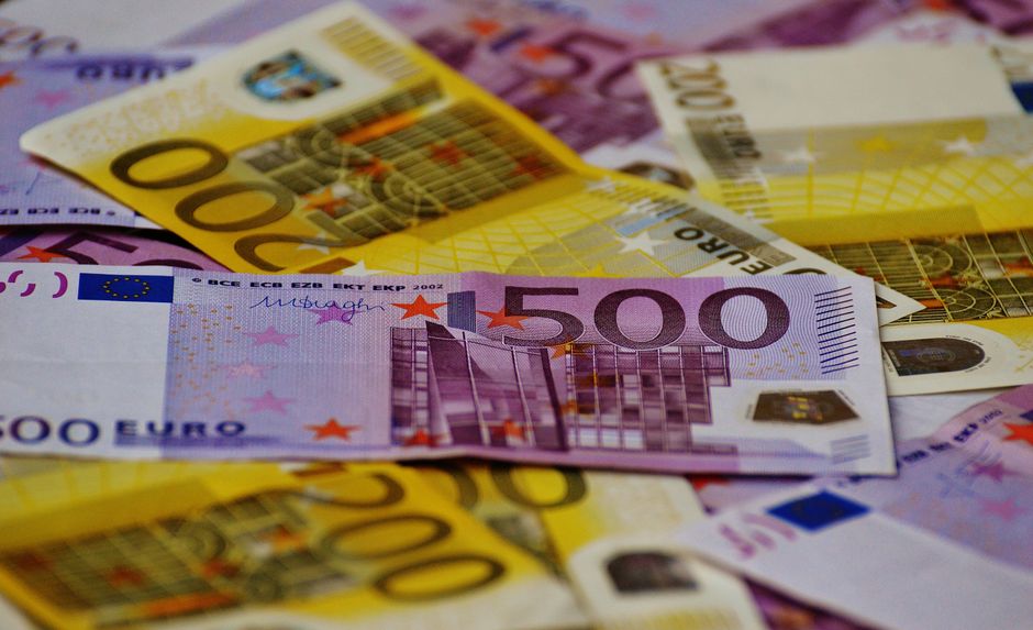 A close-up image of several Euro banknotes arranged in a scattered manner.