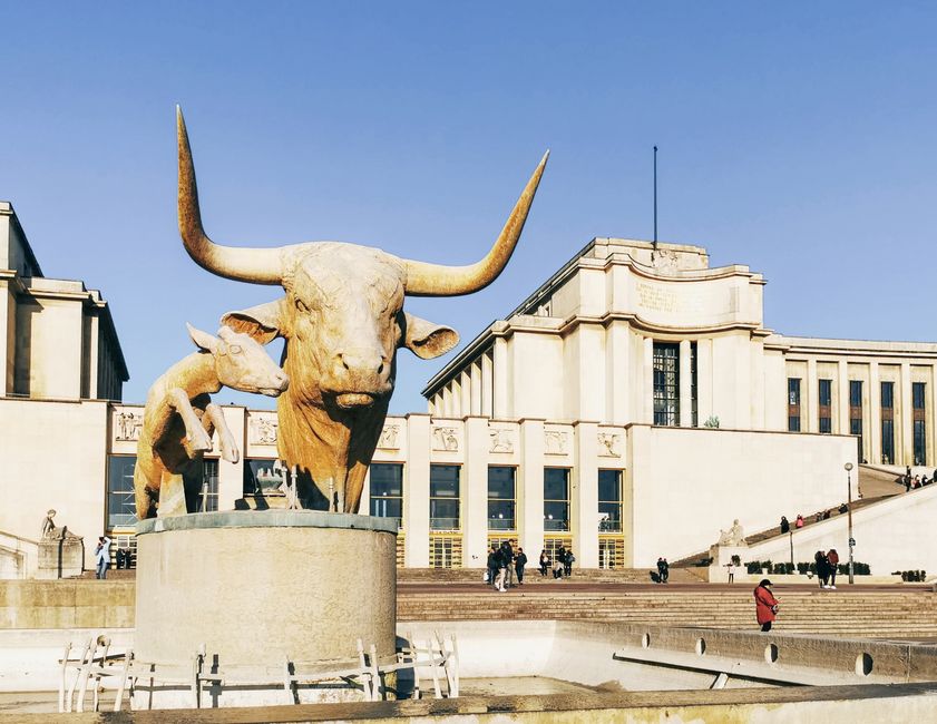 Majestic bull and calf sculpture at Palais de Chaillot, Paris, under clear blue skies.