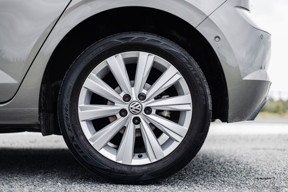 Detail of a silver Volkswagen wheel on asphalt, showcasing tire and rim design.
