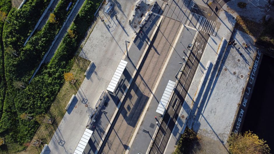 Drone shot of a modern tram station in Strasbourg, showcasing geometric design and lush greenery.