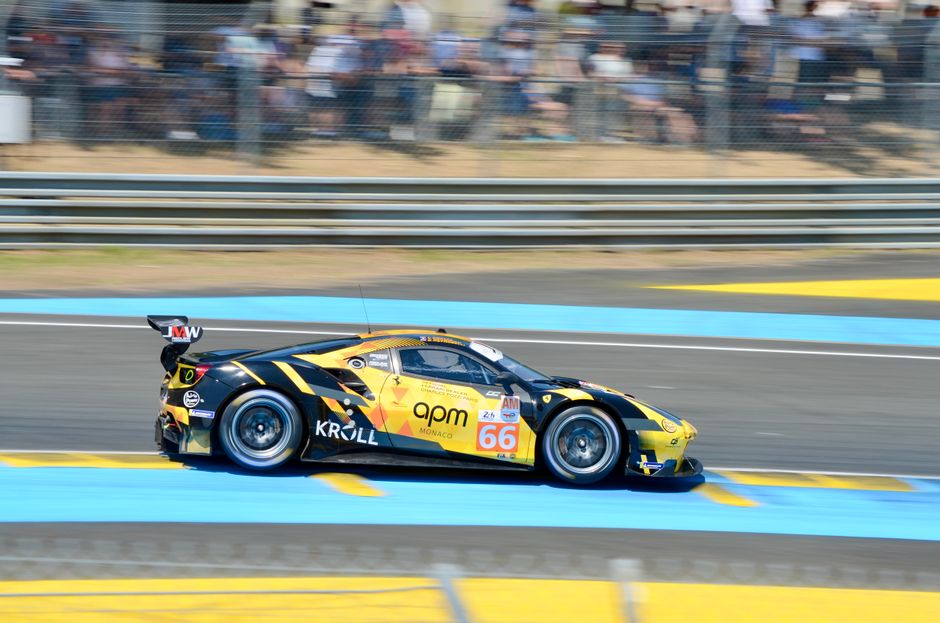 Dynamic shot of a race car speeding at Le Mans, France, showcasing vibrant colors and motion.