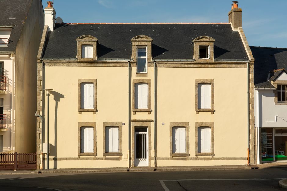 Historic townhouse facade in La Turballe, reflecting classic French architecture in warm sunlight.