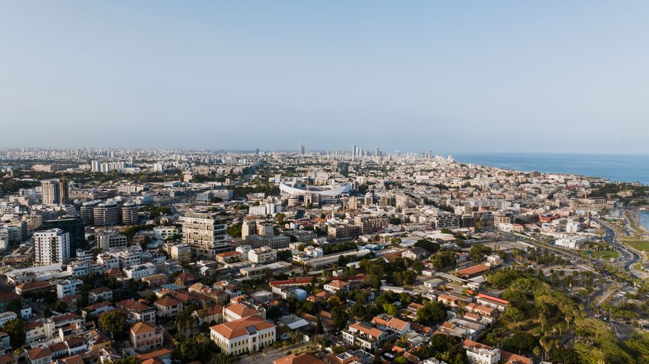 Expansive aerial cityscape of Tel Aviv-Yafo with coastal views, captured in daylight.