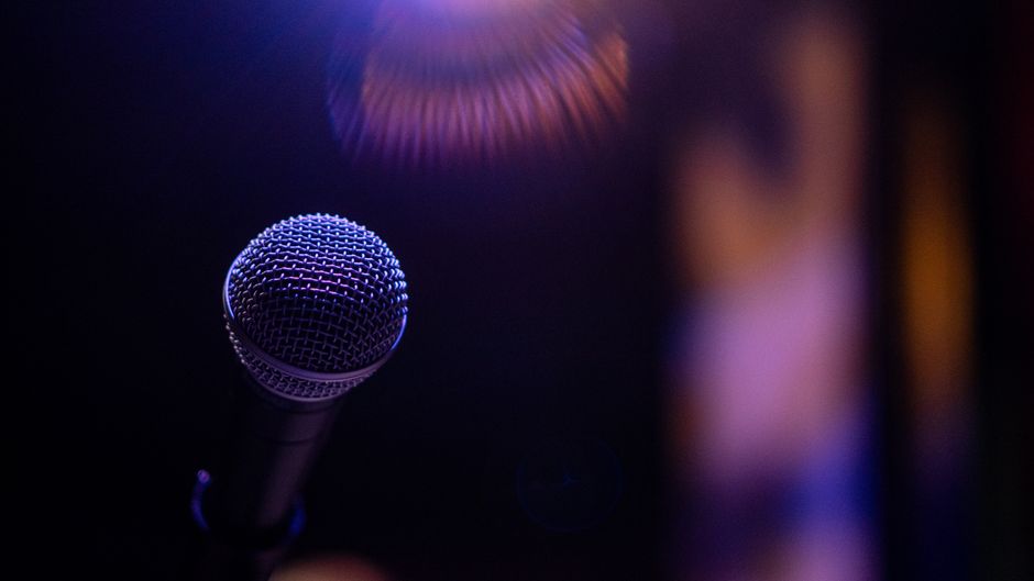 A dramatic close-up of a microphone under a spotlight, evoking performance and music vibes.