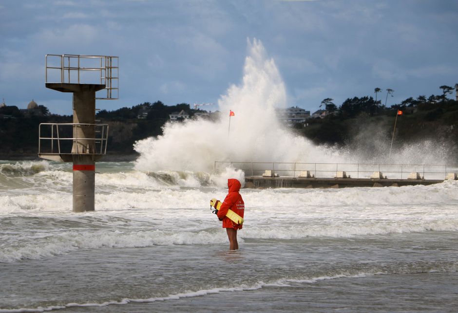 Lifeguard standing watch as large waves crash on the coast of Saint-Pair-sur-Mer, Normandy, France.