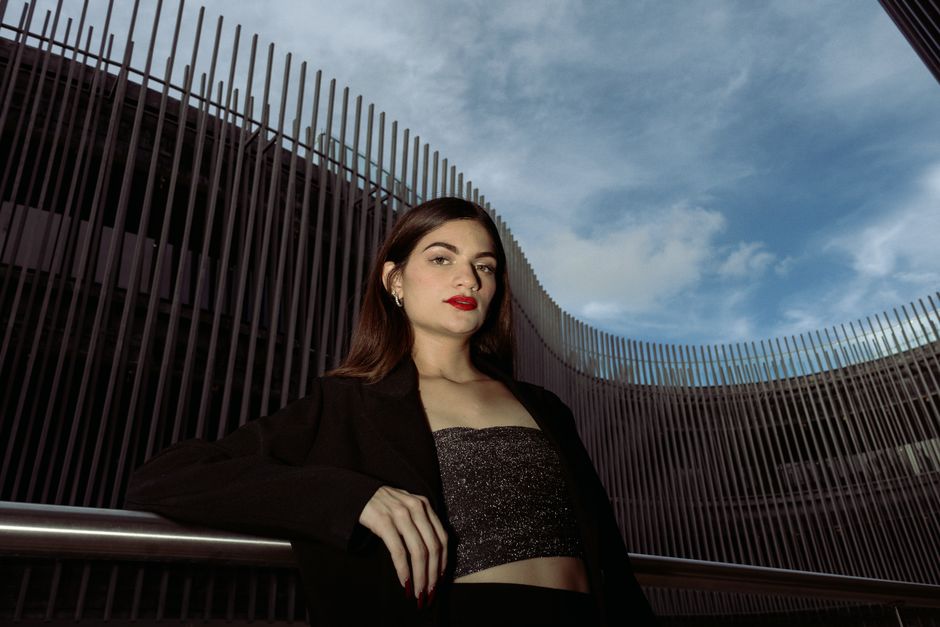 Elegant woman posing against modern architecture in Mérida, Mexico, capturing urban fashion style.