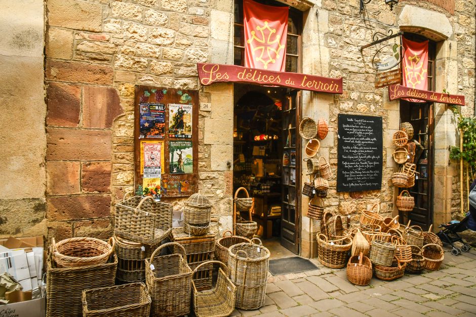 Rustic storefront featuring woven baskets at 'Les délices du terroir' in a charming stone building.