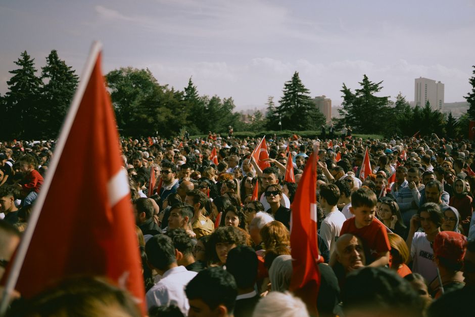 A large group of people waving Turkish flags during a daytime rally in Ankara, Türkiye.