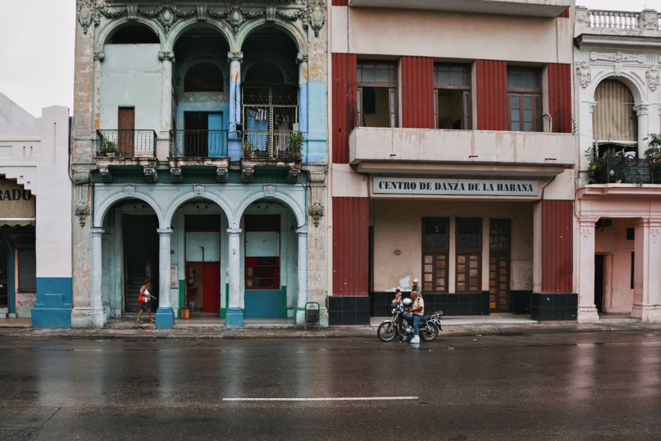 Street scene in Havana showcasing vibrant colonial architecture and a motorcycle with riders.